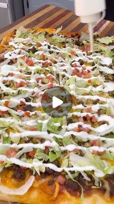 a pizza with cheese, lettuce and other toppings on it sitting on a cutting board