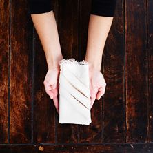 a person holding a napkin on top of a wooden floor next to a wall with wood planks