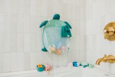 a bathtub filled with toys next to a gold faucet and shower head