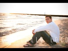 a young man sitting on the beach at sunset