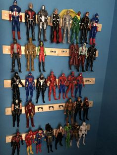 a bunch of action figures are displayed on the shelf in front of a blue wall