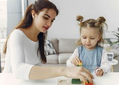 a mother and daughter playing with toys at the table