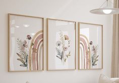 three framed art pieces hang on the wall above a couch in a room with white walls