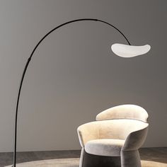 a modern floor lamp in the corner of a room with a white couch and chair