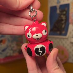 a hand holding a red and black bear keychain