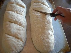 two loaves of bread being cut on a cutting board