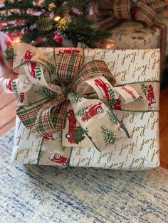 a wrapped present sitting on top of a table next to a christmas tree