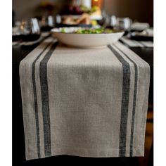 a bowl of salad on top of a table with black and white striped linens