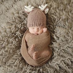 a newborn baby wearing a knitted deer hat and blanket