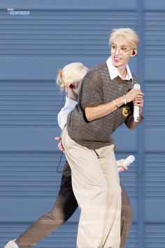 a man and woman are walking down the street with one holding a bottle in his hand