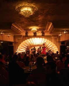 a group of people sitting at tables in front of a stage with lights on it