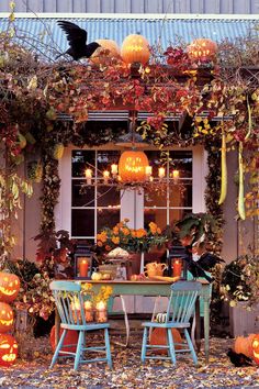 an outdoor dining area decorated for halloween with pumpkins on the table and two chairs