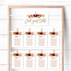 the seating chart for an autumn wedding is displayed in a wooden frame on a white wall