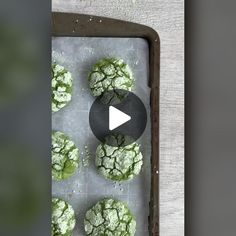 a tray filled with green cookies covered in powdered sugar