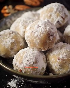 powdered sugar coated doughnuts in a bowl on a table with pecans