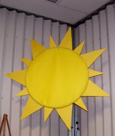 a large yellow sun hanging from the side of a building next to an easel