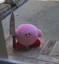 a pink teddy bear with a knife stuck in it's face on the ground