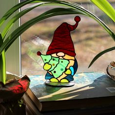 a stained glass lamp sitting on top of a table next to a plant in front of a window