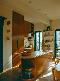 a kitchen with wooden cabinets and an island in front of two windows that look out onto the yard