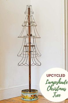 a tall metal christmas tree on top of a wooden table next to a white wall