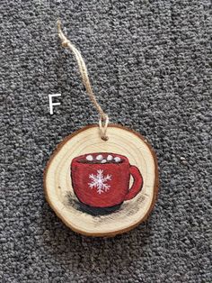 a wooden ornament with a red coffee cup on it and snowflakes