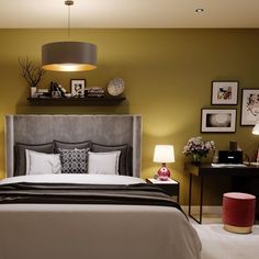 a bedroom with yellow walls and gray bedding, white carpeted flooring and pictures on the wall