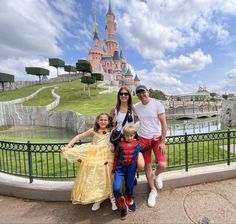 a family poses for a photo in front of the sleeping beauty castle at disneyland world