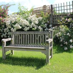 a wooden bench sitting in the middle of a lush green field next to white flowers