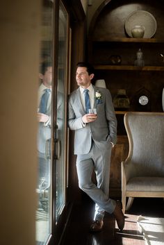 a man in a suit and tie standing next to a chair