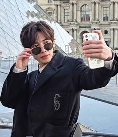 a young man taking a selfie with his cell phone in front of the pyramid