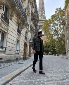 a man standing in front of the eiffel tower on a cobblestone street