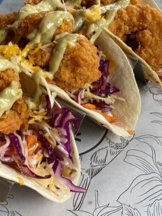 three tacos with chicken, coleslaw and sauce on them sitting on a plate