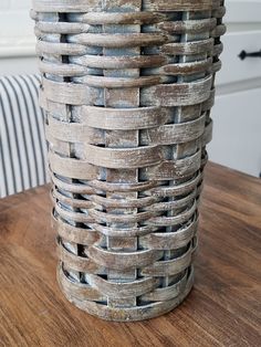 a wooden table topped with a tall vase filled with lots of woven material on top of it