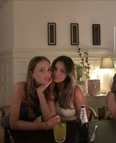 two beautiful young women sitting at a table with drinks