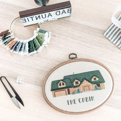 a cross stitch pattern with the words the cabin on it next to some scissors and thread