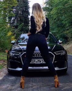 a woman standing in front of a black car