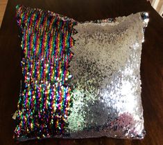 two sequin pillows sitting on top of a wooden table