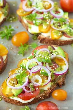 several sandwiches with tomatoes, onions and lettuce on them