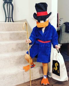 a person in a blue robe and hat with a cane standing on the stairs next to a bag