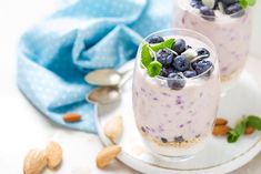 two desserts with blueberries, almonds and mint on a white plate next to a blue towel