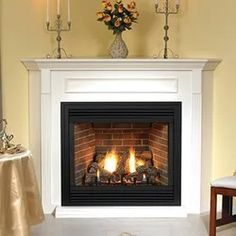 a fire place in a living room with candles on the mantle and flowers sitting on top