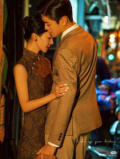 a man and woman standing next to each other in front of a building at night