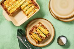 two plates with slices of vegetable lasagna on them next to utensils