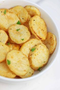 a white bowl filled with cooked potatoes on top of a table