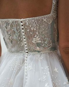 the back of a woman's wedding dress with beading and pearls on it