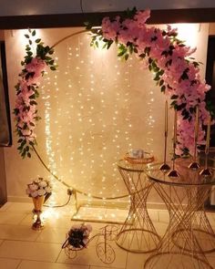 a table with flowers on it and lights in the back ground behind it, along with two chairs