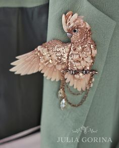 a close up of a bird brooch on a green shirt