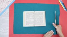 a woman is cutting out an open book with scissors