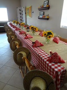 a long table is set up with sunflowers and red checkered cloth on it