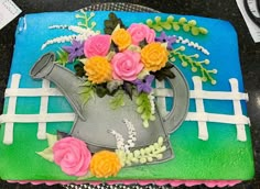 a cake decorated with flowers and a watering can